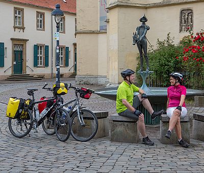 Zwei Personen sitzen vor einem Springbrunnen 